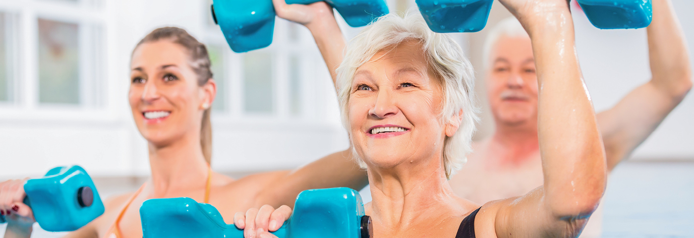Medizin & Therapie - Dreiergruppe mit Hanteln beim Training im Wasser